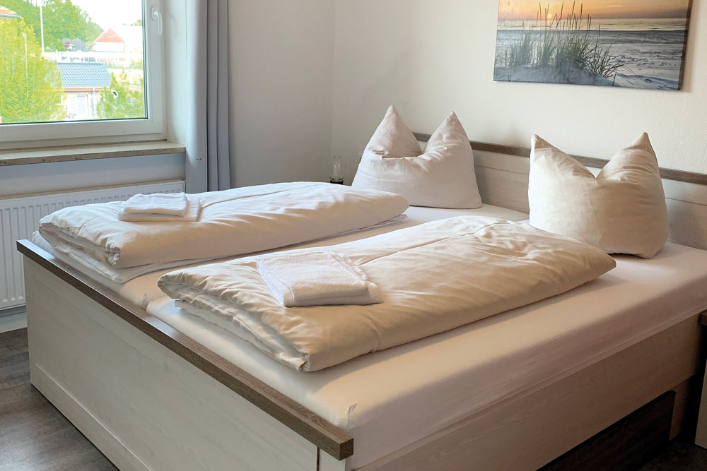 Doppelbett mit weißer Bettwäsche