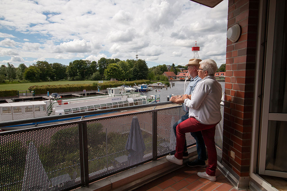 Zwei Gäste schauen vom Balkon auf das Wasser